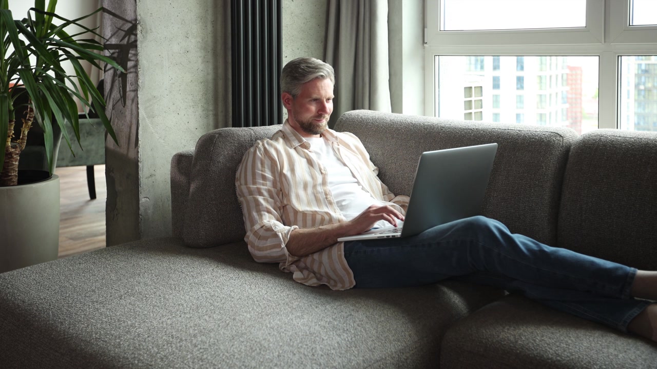 Focused Man Using Laptop on Comfortable Sofa at Home