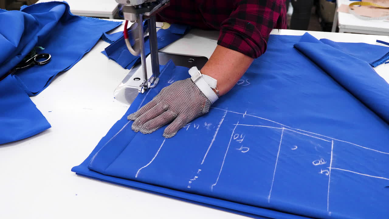 trabajadora que usa una herramienta para cortar tela en una fábrica textil