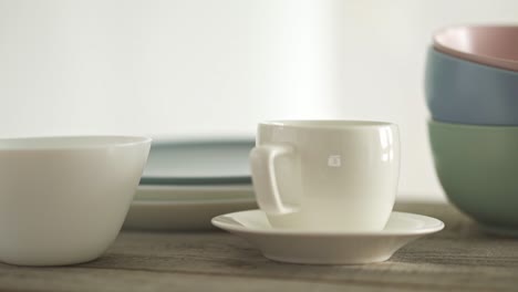 a large set of clean dishes. a stack of white and gray plates and a coffee cup and saucer. three bowls one on top of the othe