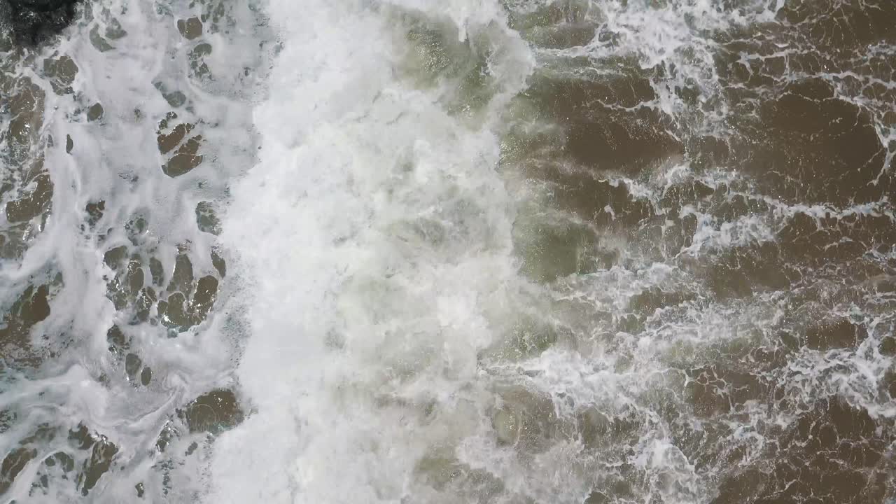 vista aérea de arriba hacia abajo sobre las olas rompiendo en rocas sumergidas