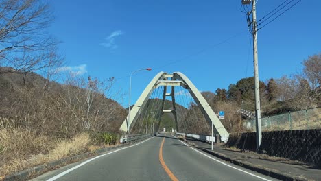 vehicle driving over a bridge on the quiet backroads of rural japan. the scene showcases the peaceful and traditional landscape, emphasizing the charm of countryside travel and infrastructure