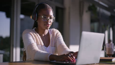 woman working on laptop with headphones and writing