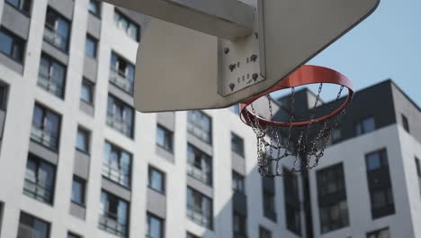 orange basketball hits basket, basketball court on street,sunny day