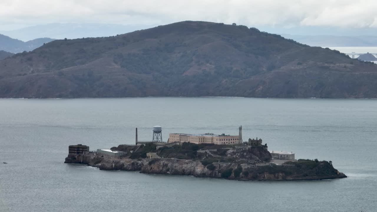 Alcatraz Island in San Francisco Bay with Angel Island backdrop on cloudy day