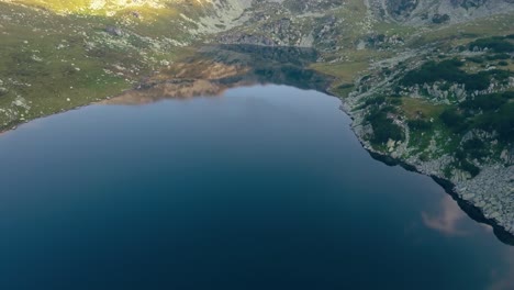 Breites-Luftbrummen-über-Einem-See,-Der-Langsam-Nach-Rechts-Zu-Einer-Bergkette-Abbiegt