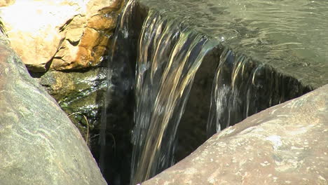 water flows over the brink of a small waterfall