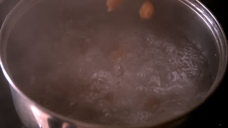 pasta falling into saucepan of boiling water