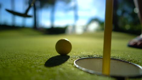 Gelber-Minigolfball-Mit-Einem-Schläger-In-Der-Nähe-Des-Lochs-Bei-Sonnenuntergang