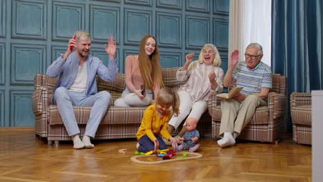 a happy family with a little girl playing with a train set in their living room.