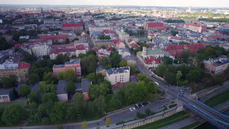 Aerial-flyover-neighborhood-in-Cracow-with-driving-cars-on-road-during-sunny-day,Poland