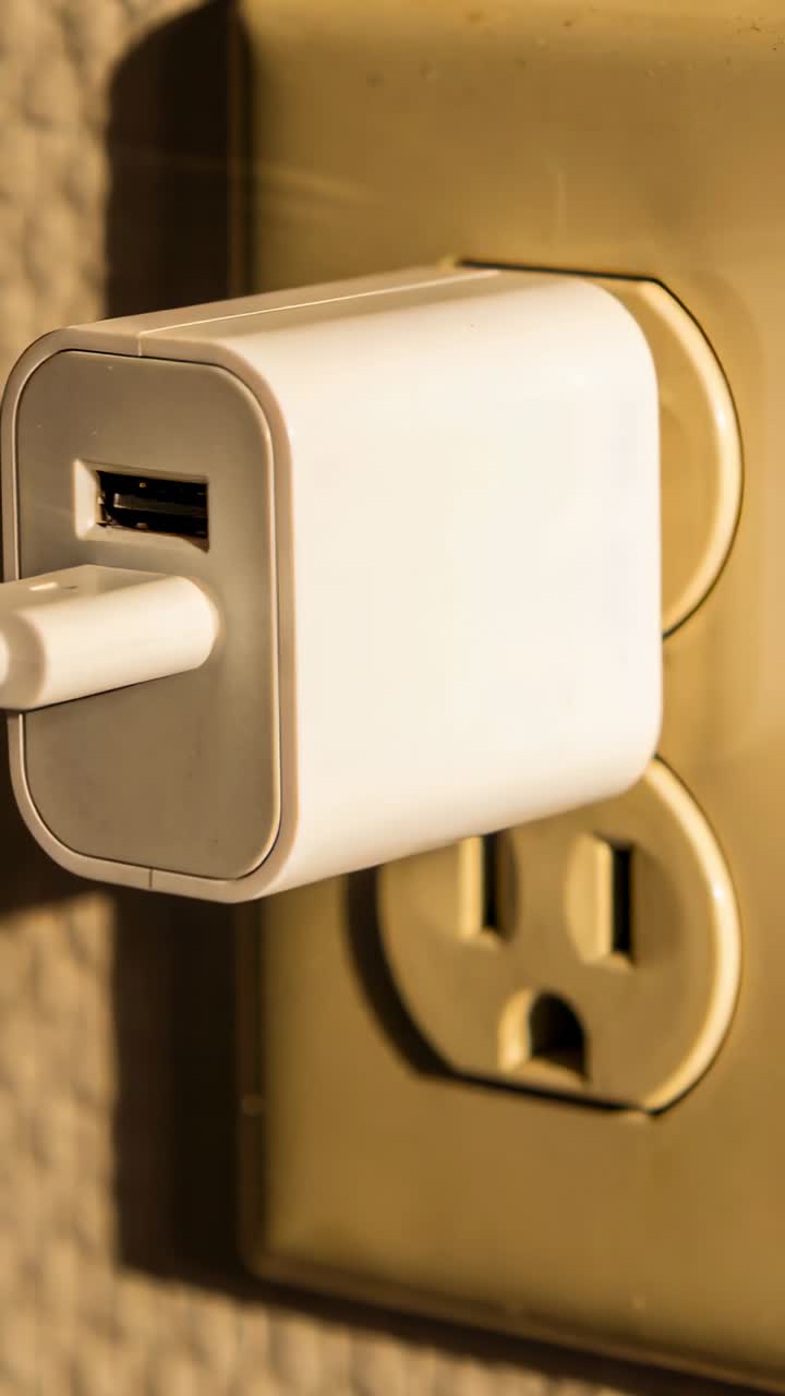 Vertical video: Shifting camera to reveal USB adapter with cable on brass plate at home