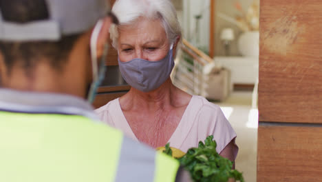 Lieferbote-Liefert-Lebensmittel-An-ältere-Kaukasische-Frau-Mit-Gesichtsmasken-Zu-Hause