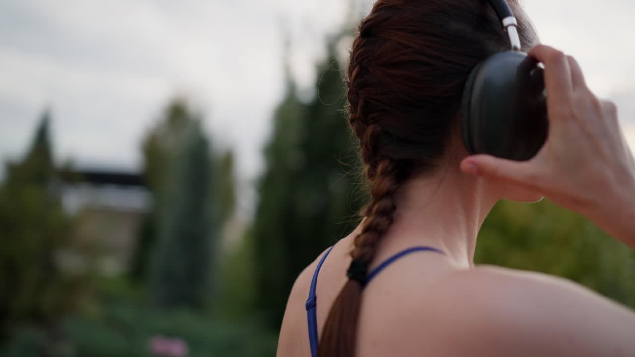 Mujer caminando en un parque con auriculares