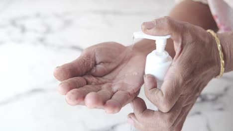 elderly person applying hand sanitizer