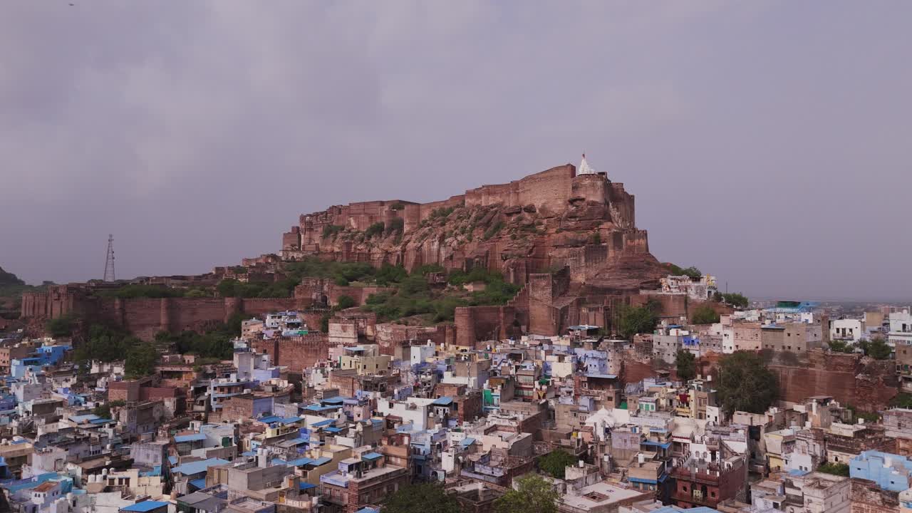 Jodhpur, the blue city, with the majestic Mehrangarh Fort in background. Drone aerial rotate late afternoon.