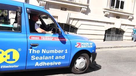 a blue taxi driving through a london street