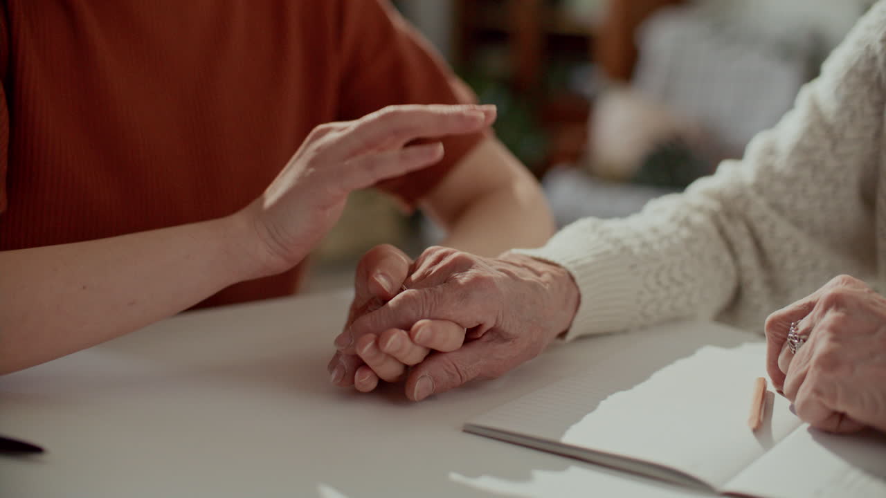 Caregiver Supporting Elderly Woman and Holding Her Hand during Conversation