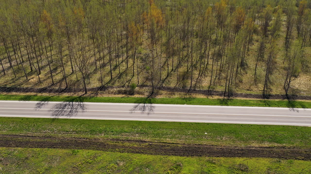 toma aérea de dos autos negros en el camino a través del paisaje boscoso