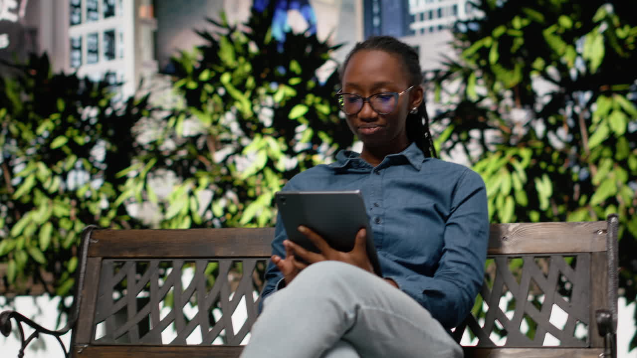 African american freelancer outside using tablet on park bench