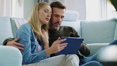 pareja amorosa usando una tableta en la sala de estar