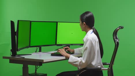 woman working at a computer with multiple monitors