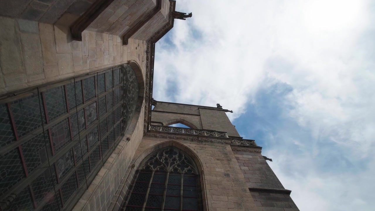 Facciata gotica in pietra e gargoyle della Cattedrale di Limoges sotto un cielo azzurro con nuvole. Prospettiva dal basso che mostra l'edificio religioso storico nella città
