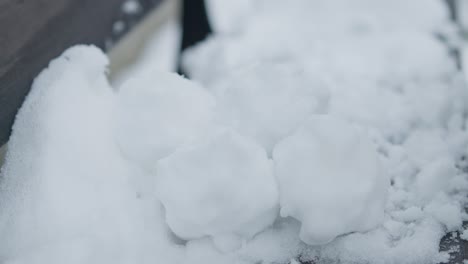 Slowmotion-closeup-of-grabing-and-removing-pile-of-snowballs-with-black-gloves