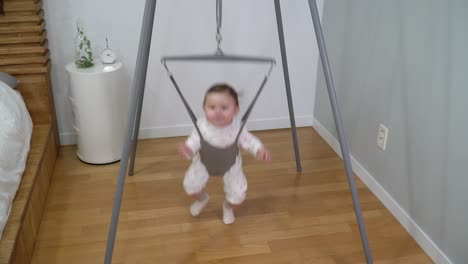 slow-motion of little baby girl exercise in a jolly jumper in bedroom