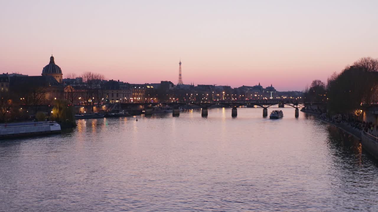 Panning wide shot of romantic Paris Seine river during sunset with pink sky and boats
