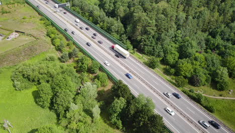 aerial top down shot of traffic and traffic jam on rural highway surrounded by forest and fields at sun