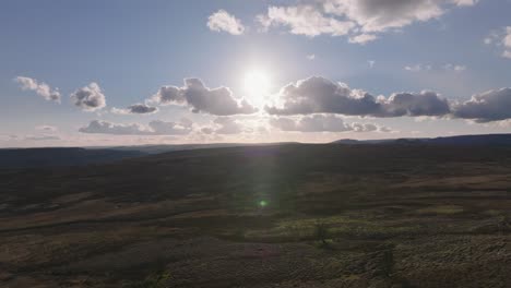 beautiful aerial drone footage descending over wide, open moorland in autumn with a low sun in a blue sky