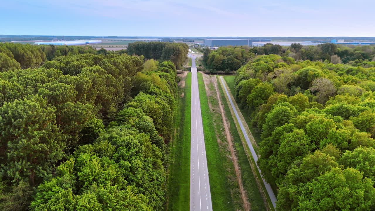 Straight two-lane road away from the cities. Drone footage over the highway in the countryside across the forest.