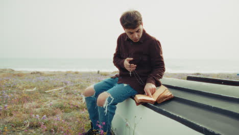 christian man reading a prayer on the bible book while on the beach