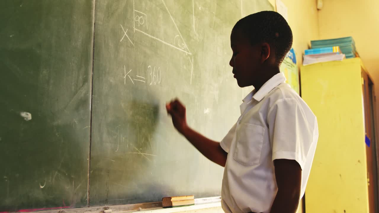 Young schoolboy writing on the blackboard in class 4k