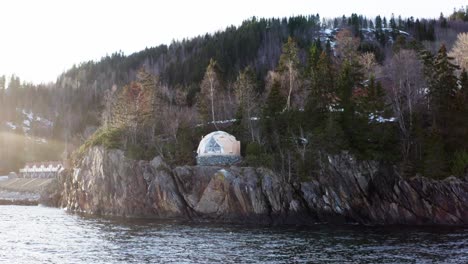 arctic dome tent atop on rocky cliff ocean at sunrise in norway