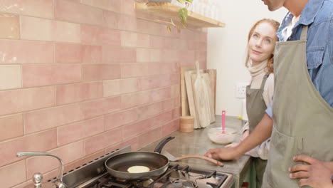 diverse couple cooking pancakes together in kitchen, enjoying quality time, copy space