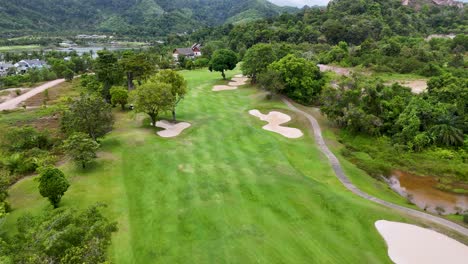 aerial views of a lush golf course in phuket, showcasing vibrant greens, sand bunkers, and surrounding tropical landscape