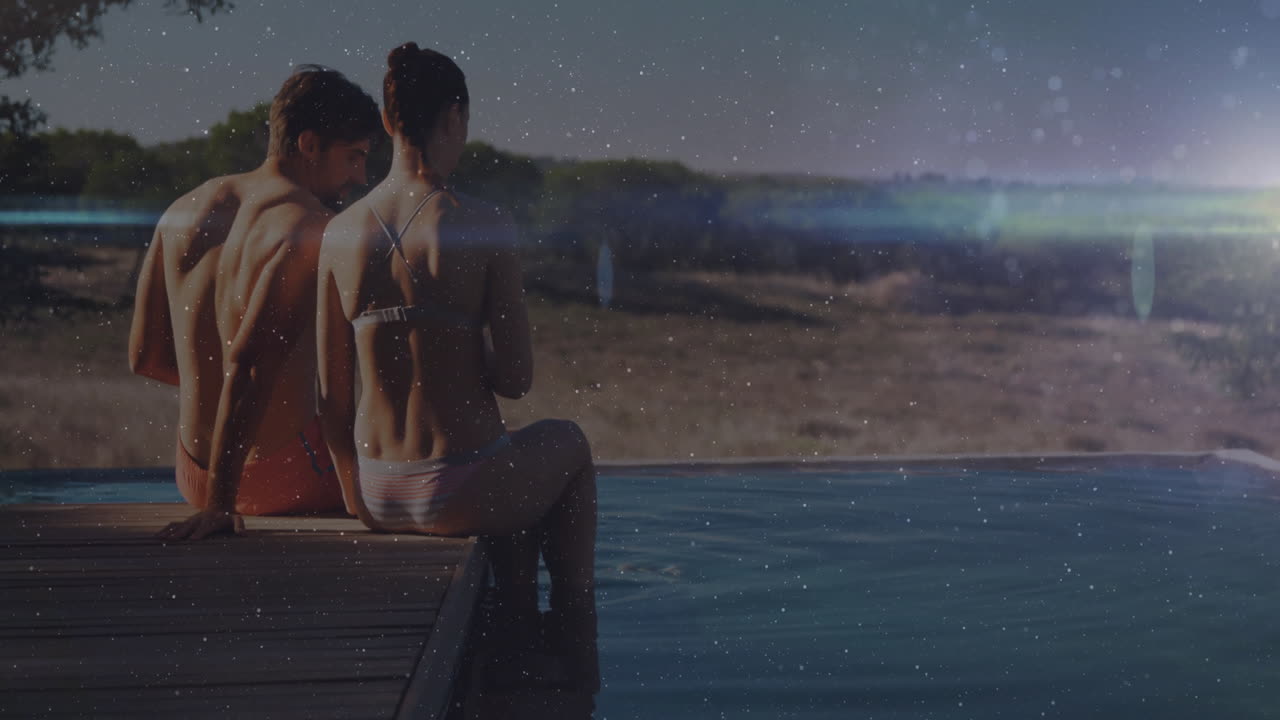 Two people sitting by poolside with sparkling animation over scenic landscape