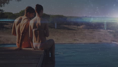two people sitting by poolside with sparkling animation over scenic landscape