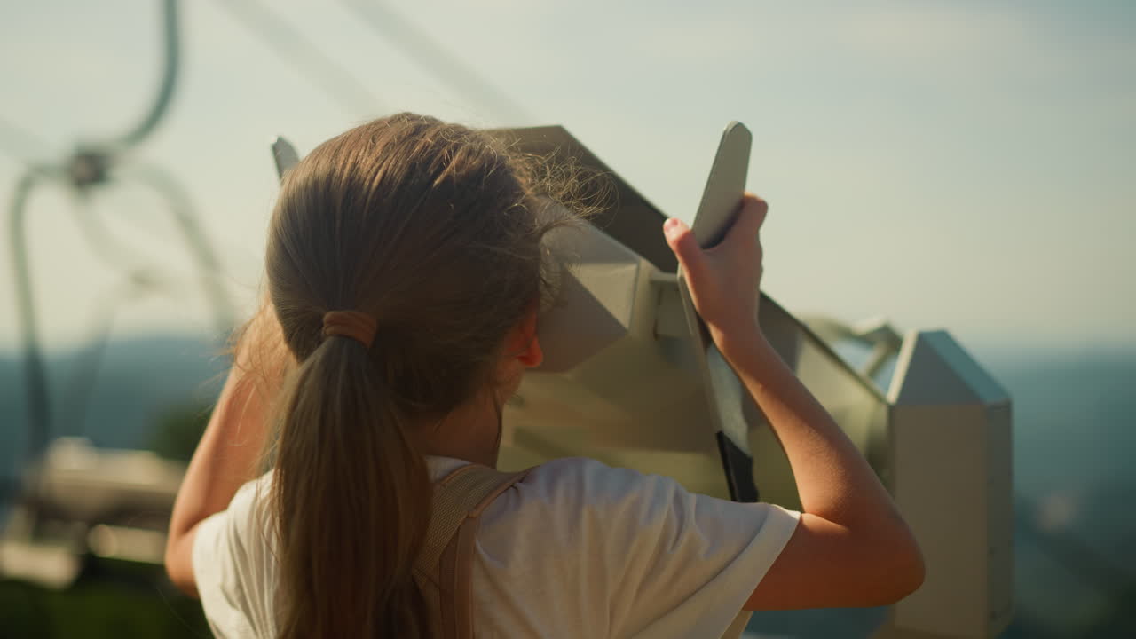 소녀는 산에서 안경을 통해 관광 지역을 조사합니다. 환경의 아름다움과 호기심. 세계 느린 움직임에 관심이있는 유치원