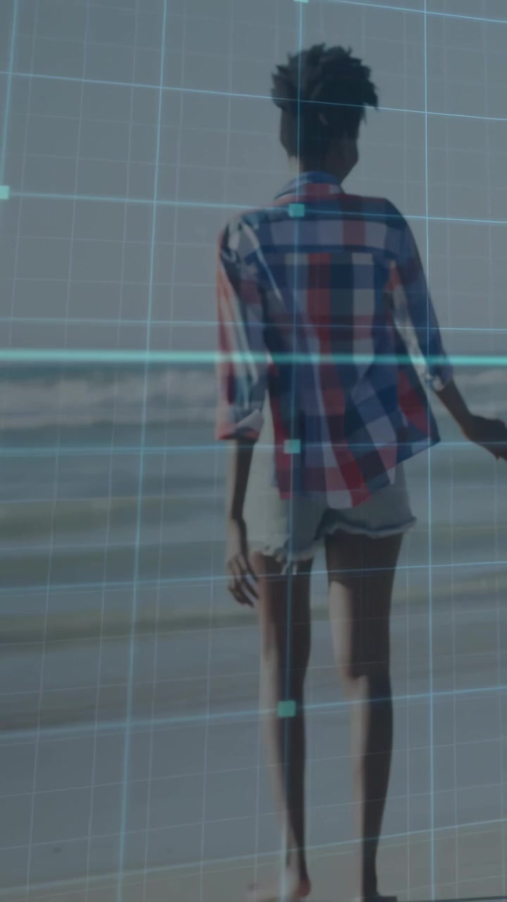 Vertical video: Woman walking shore while blue grid appearing, aligning with body, showcasing tech