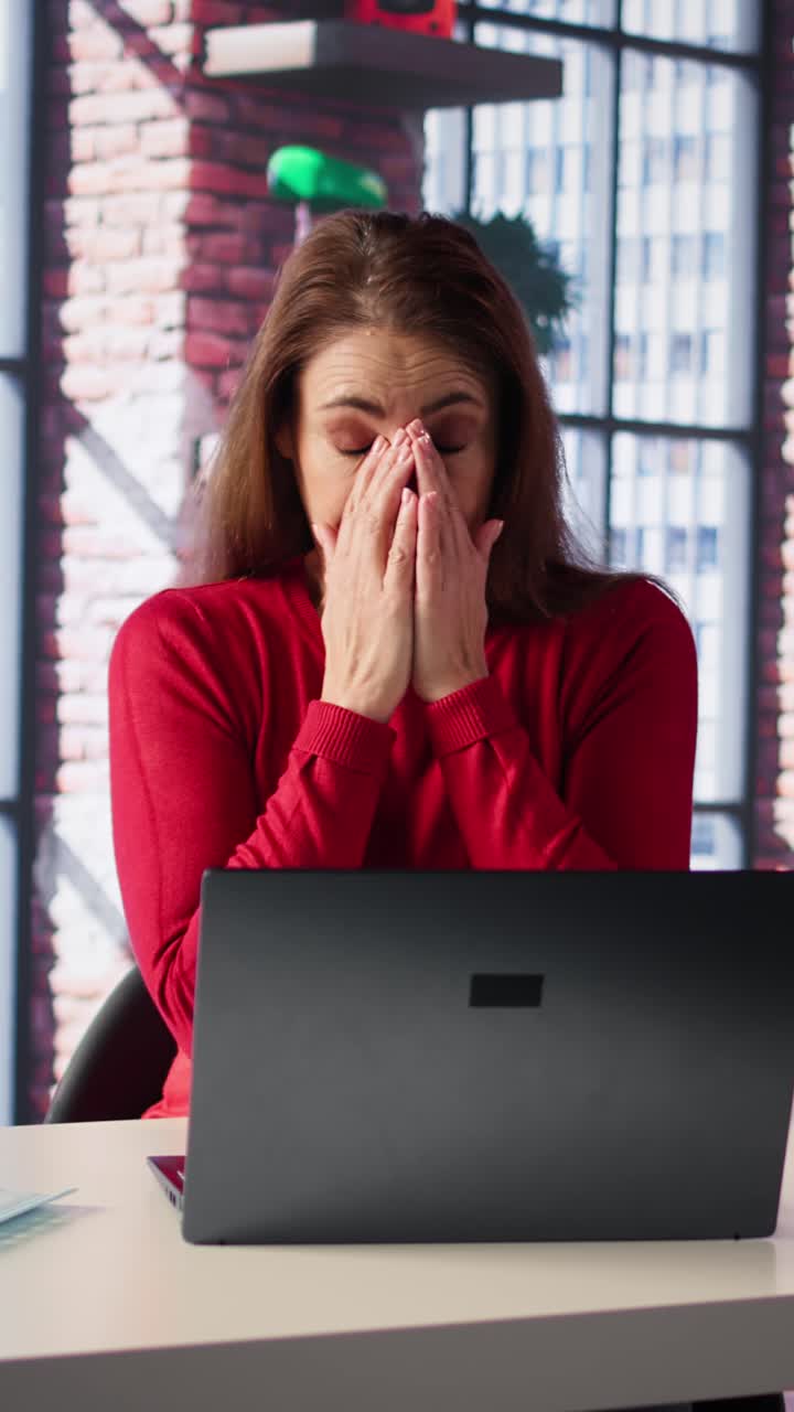 Vertical Video Exhausted woman trying to solve daily tasks on laptop at home office