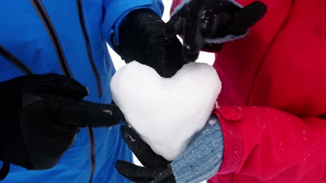 mid section of couple making snow heart