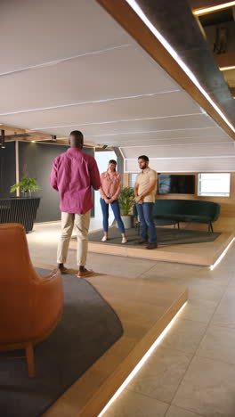 vertical video: business meeting, three colleagues discussing project in modern office space