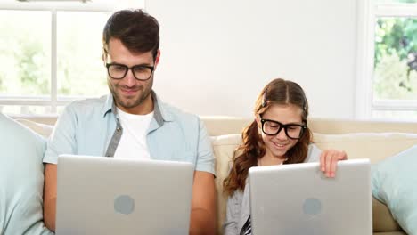 padre e hija usando computadora portátil en la sala de estar