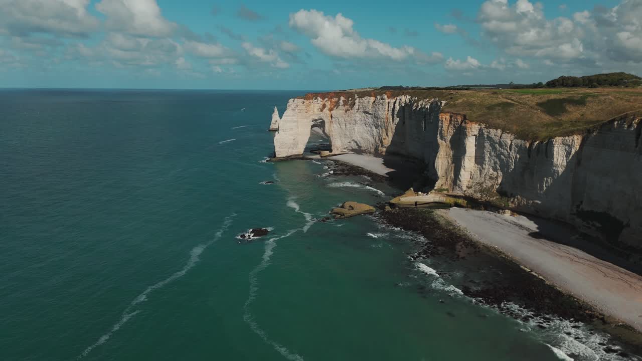 Drone shot of Étretat’s white chalk cliffs and natural arch stretching along the Normandy coast