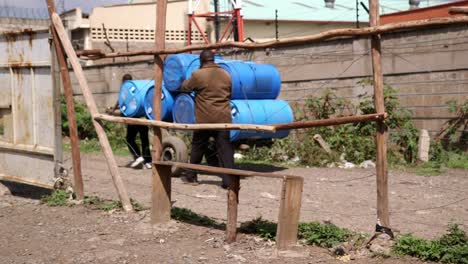 man drags big water barrels on a cart in africa