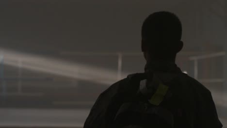 person walking in a dark, foggy interior