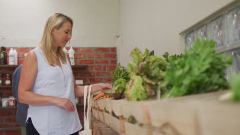 video of caucasian woman picking up fresh organic carrots in grocery shop