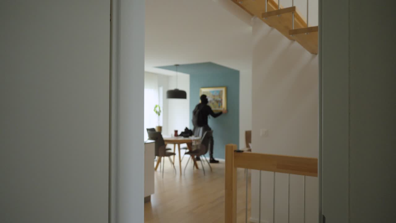 Un ladro irrompe in una casa di giorno e ruba un quadro incorniciato dal muro prima di fuggire. Un concetto per crimini contro il patrimonio, sicurezza domestica, perdita assicurativa e indagine
